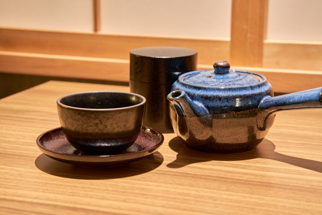 家庭の食卓に置おかれた湯のみと急須と茶筒